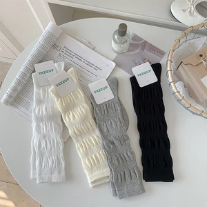 Detail view of ribbed knit leg warmers in white, beige, grey, and black colors