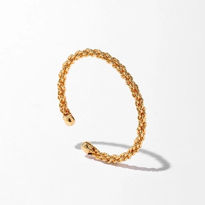 Gros plan du bracelet en or torsadé avec des embouts sphériques lisses sur fond blanc