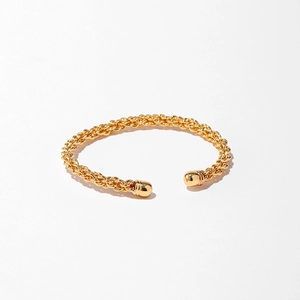 Gros plan détaillé d'un bracelet manchette torsadé plaqué or avec embouts perlés