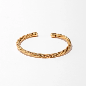 Détail d'un bracelet ouvert torsadé doré avec des embouts sphériques polis en gros plan