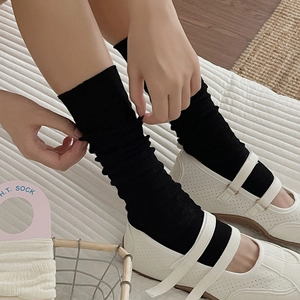 Close-up of ballet style ribbed leg warmers paired with white Mary Jane shoes