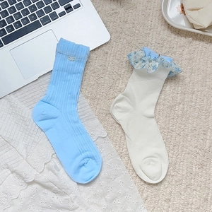 Détail de chaussettes en tricot bleu et blanc avec bordure en dentelle fleurie et nœuds