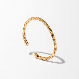 Détail du bracelet rigide torsadé avec finition dorée polie et extrémités sphériques