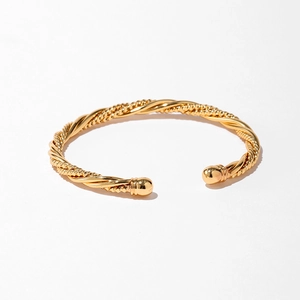 Détail du bracelet doré torsadé avec fil métallique à trois brins et embouts sphériques