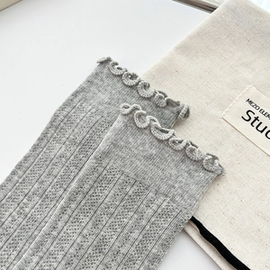 Detail of light gray ribbed crew socks with delicate scalloped edges on a beige fabric