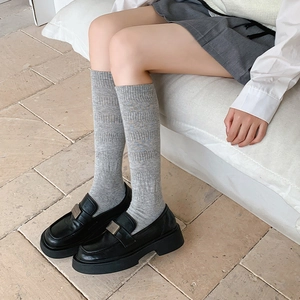 Detail of grey ribbed knit knee high socks paired with black platform loafers shoes