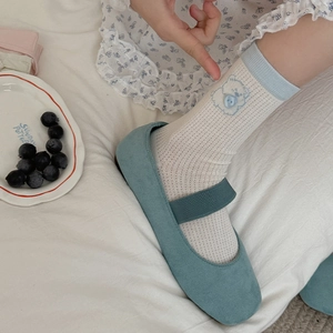 Détail de chaussettes mi-mollet côtelées blanches avec broderie ours et bord bleu