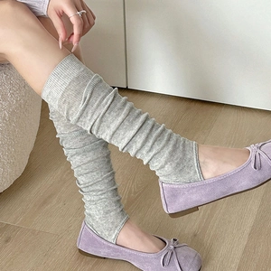 Gros plan de jambières en tricot gris clair avec nervures et chaussures plates mauves