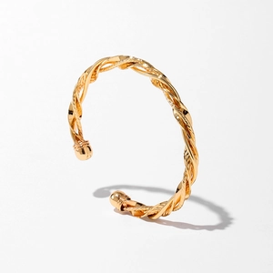 Détail d'un bracelet doré torsadé avec texture tressée et extrémités sphériques