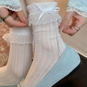 Détail de chaussettes en dentelle blanche avec nœuds en soie et texture en maille verticale
