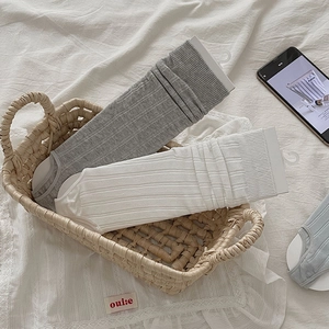 Close-up of ribbed knit crew socks in grey and white colors placed in a woven basket