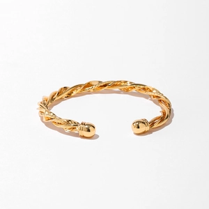 Détail du bracelet torsadé doré avec texture tressée et embouts sphériques sur fond blanc
