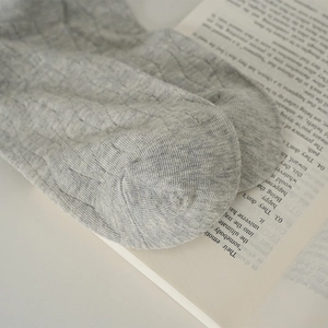 Dettaglio ravvicinato di calze grigie in maglia a coste distese su un libro d'epoca