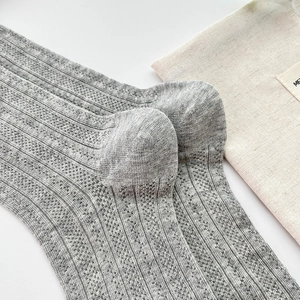 Detail of grey knitted mid-calf socks with vertical openwork stripes and cotton texture