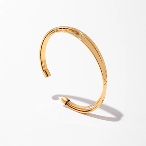 Détail d'un bracelet doré avec doubles bandes parallèles et texture métallique martelée