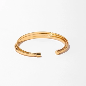 Détail d'un bracelet manchette doré à trois couches avec une finition martelée mate