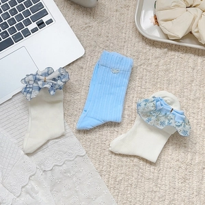 Détail de chaussettes à dentelle blanc et bleu avec nœuds à carreaux et motifs floraux