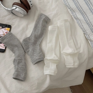Close-up of ribbed knit texture on white and grey stirrup leg warmers on a bed