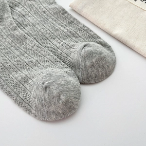 Close-up of grey knitted socks showing the breathable hollow stripe pattern and toe detail