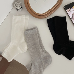 Close-up of ribbed knit texture on white, grey and black crew socks in a cozy setting