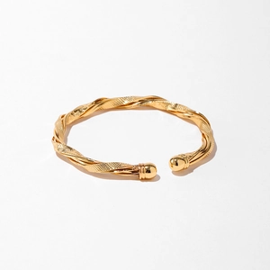 Détail d'un bracelet torsadé doré avec texture mate et extrémités sphériques lisses