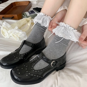 White ballet style socks with lace ruffles and bows worn with black Mary Jane shoes