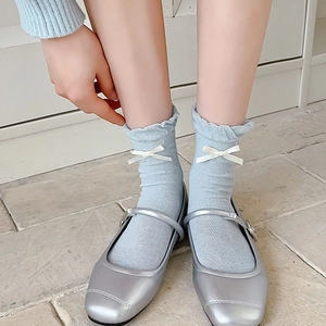 Detail of light blue bow socks with ruffled cuffs and silver Mary Jane shoes