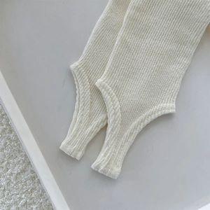 Close-up of beige ribbed knit leg warmers with thumb hole design and soft texture