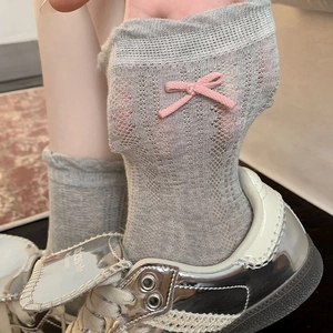 Close-up of grey breathable mesh socks featuring a pink bow detail and hollow knit texture