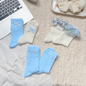 Détail de chaussettes style collège avec dentelle et nœuds en ruban en bleu et beige clair