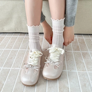 Detail of pearlescent ballet flats with satin ribbon laces and lace-trimmed socks