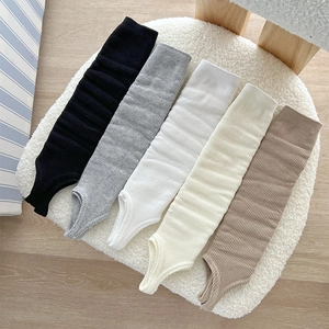 Detailed close-up of ribbed knit leg warmers in various neutral colors on a soft mat