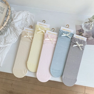 Detail of five pairs of pastel mesh socks with ribbon bows and lace trim on wooden background