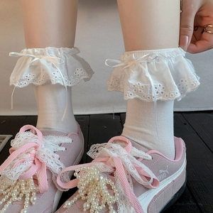 Detail of white ruffle socks with eyelet embroidery and ribbon bow in ballet style