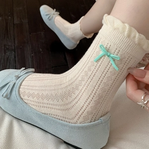 Detail of hollow-out knit cotton socks with a mint green bow and ruffled cuff edges