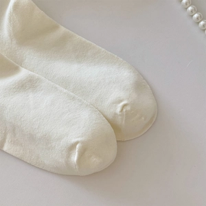 Detailed close-up of white knitted cotton sock toe showing fine stitching and texture