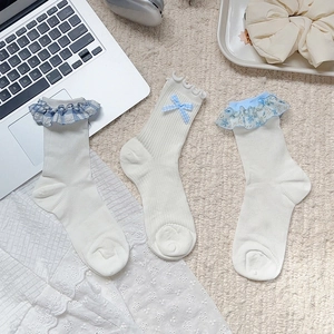 Détail de dentelle florale et nœuds sur des chaussettes mi-hautes en coton bleu et blanc