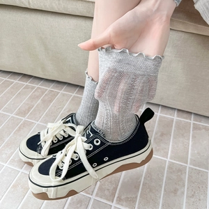 Close-up of sheer grey ribbed socks with ruffled edges showing elasticity and texture