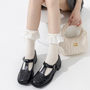 Detail of white lace ruffle socks with ribbon bow, paired with black Mary Jane shoes