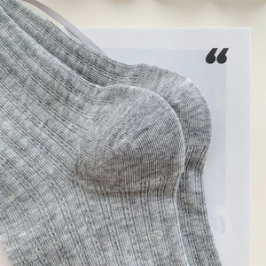 Gros plan de chaussettes en maille grise montrant la texture du talon et le tissage