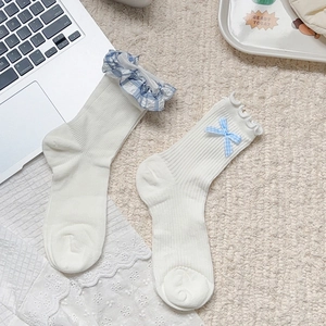Détails de chaussettes blanches côtelées avec bordure fleurie bleue et jolis nœuds