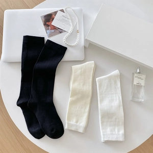 Flat lay of ribbed cotton socks in black, white and beige on minimalist desk setup