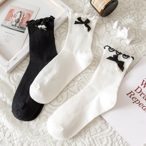 Detail of Lolita style mid-calf socks with ruffle trim, silk bows and pearl accents