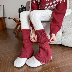 Red ribbed knit leg warmers with ribbon bow ties paired with white slippers