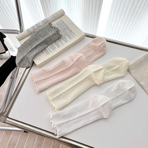 Detail of four-color ruffled mid-calf socks with vertical ribbed texture on white surface