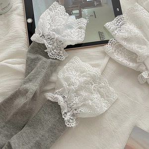 Detailed view of grey knitted leg warmers with delicate white lace trim on white fabric