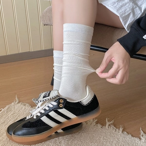Detail showing the elastic ribbed texture and stretch of white calf-length jk style socks