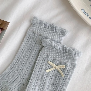 Detail of light blue mesh socks featuring ruffle lace cuffs and small cream bow accents