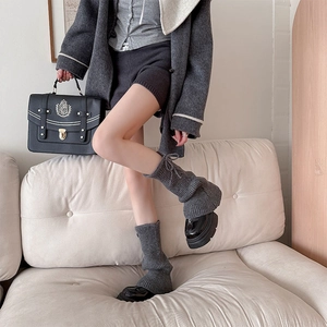 Detail view of gray ribbed knit leg warmers paired with chunky black platform shoes