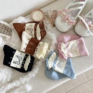 Detail of vintage bow pattern socks with cream lace ruffles on a cozy plush surface